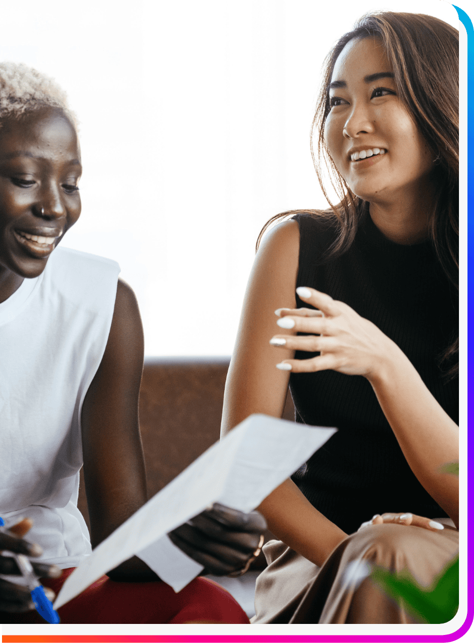Two women staffing employees smiling and looking at Onward Search diversity, equity, and inclusion document