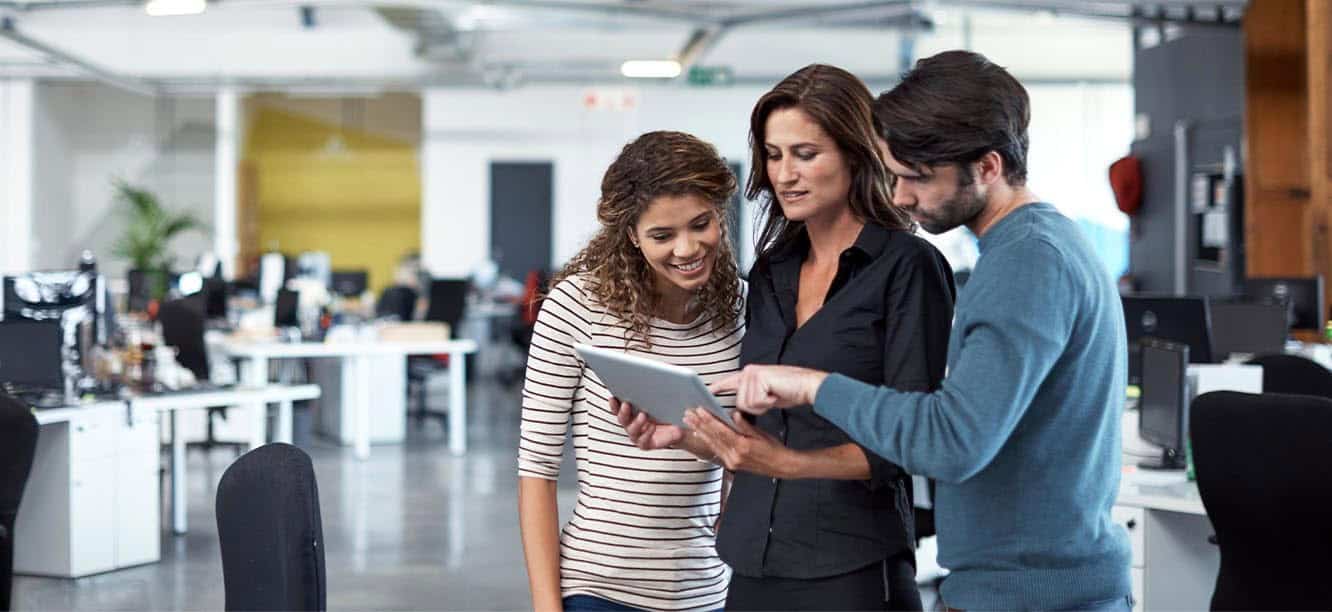 Three marketing professionals looking at tablet for creative jobs in Boston
