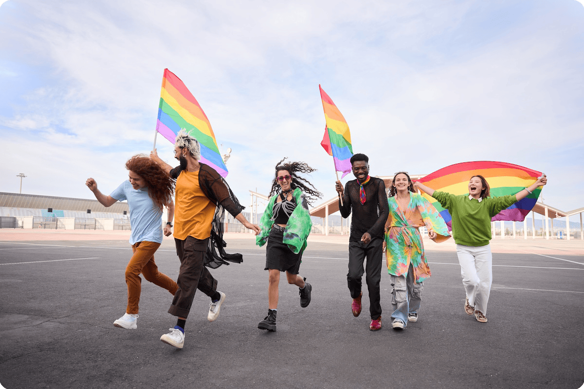 Group of creative professionals walking on the street holding pride flags.
